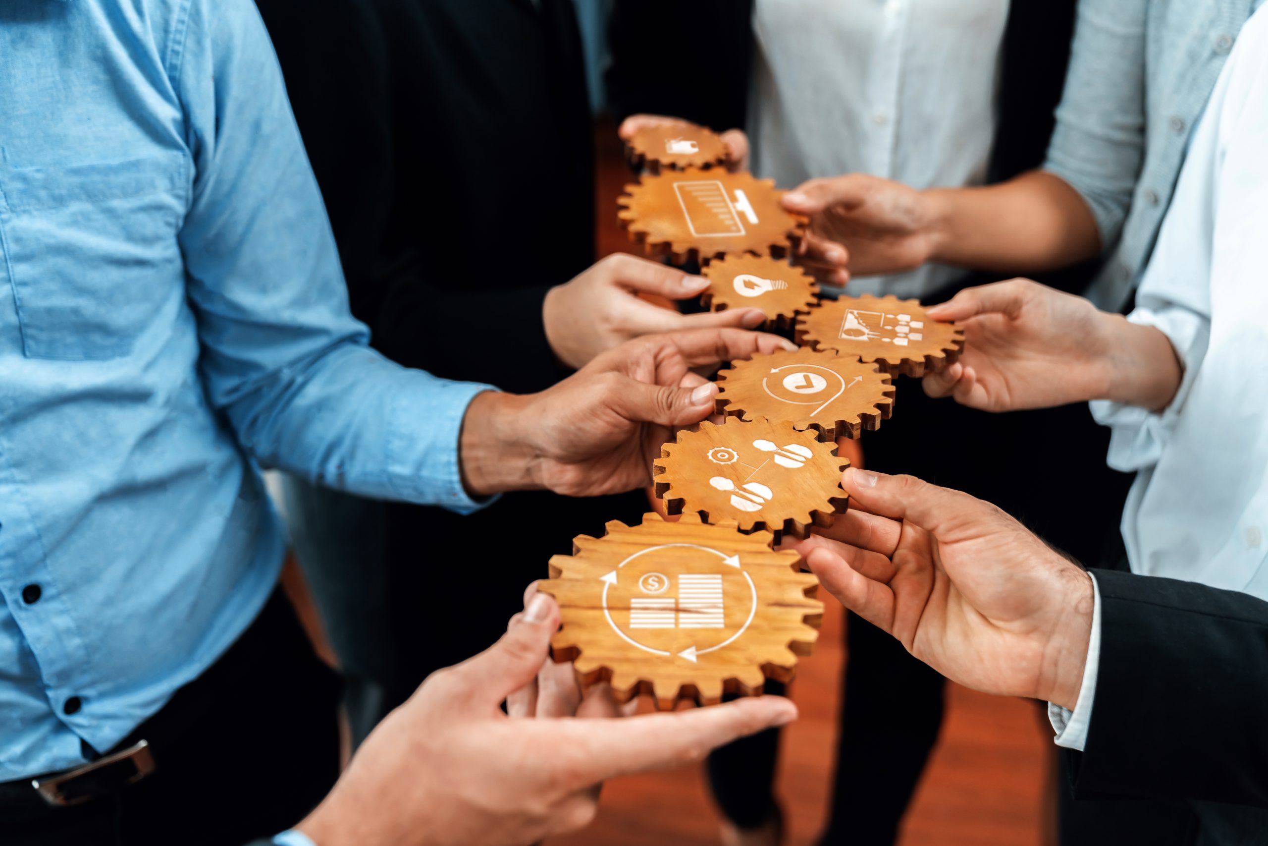 Collaborative Teamwork Concept with Hands Holding Wooden Gears Featuring Various Icons Symbolizing Ideas and Solutions. Amity